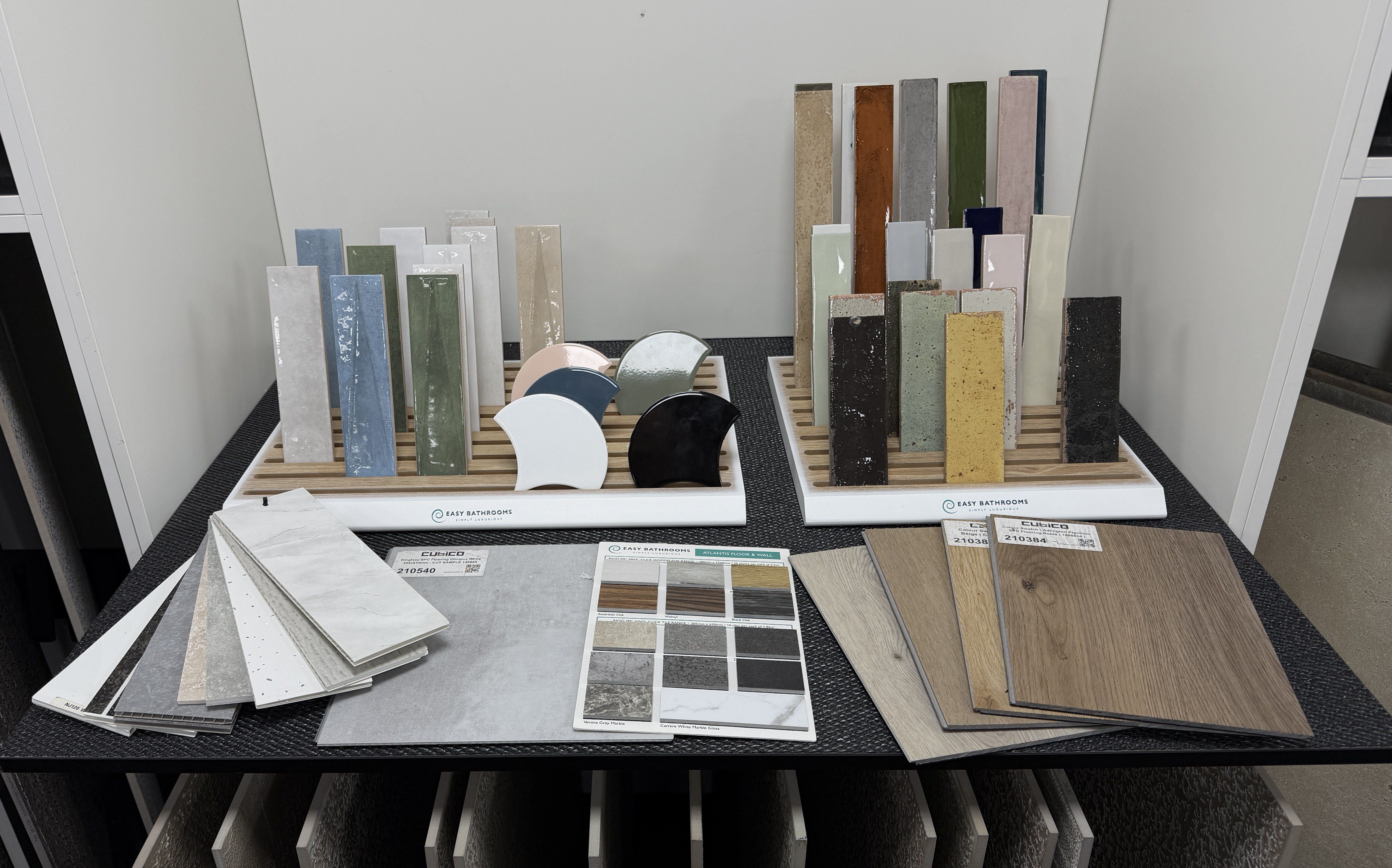 Close-up of bathroom tile samples showing gloss metro tiles, terrazzo-effect finishes, curved feature tiles and wood-effect flooring options.
