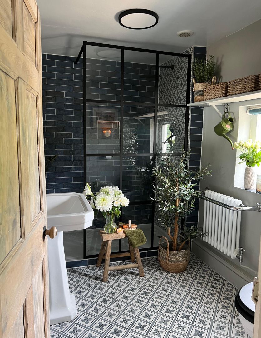 A traditional bathroom featuring Napoli Marine gloss brick wall tiles, a Matt Black grid-framed shower screen, and a Claydon white pedestal basin on patterned floor tiles.