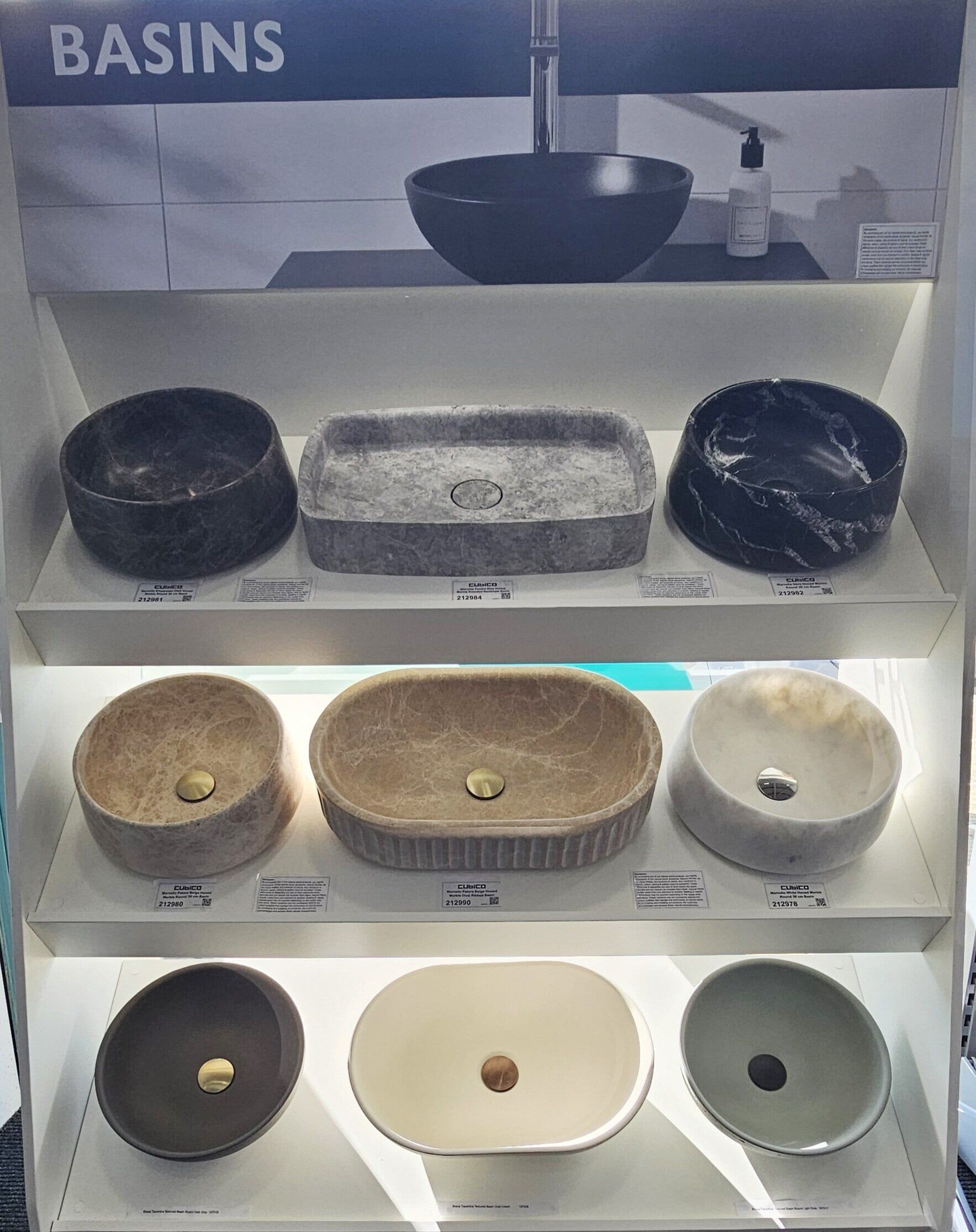 Countertop basin display at Easy Bathrooms Crawley showing a range of marble, concrete and stone-effect bowls in different colours and shapes.