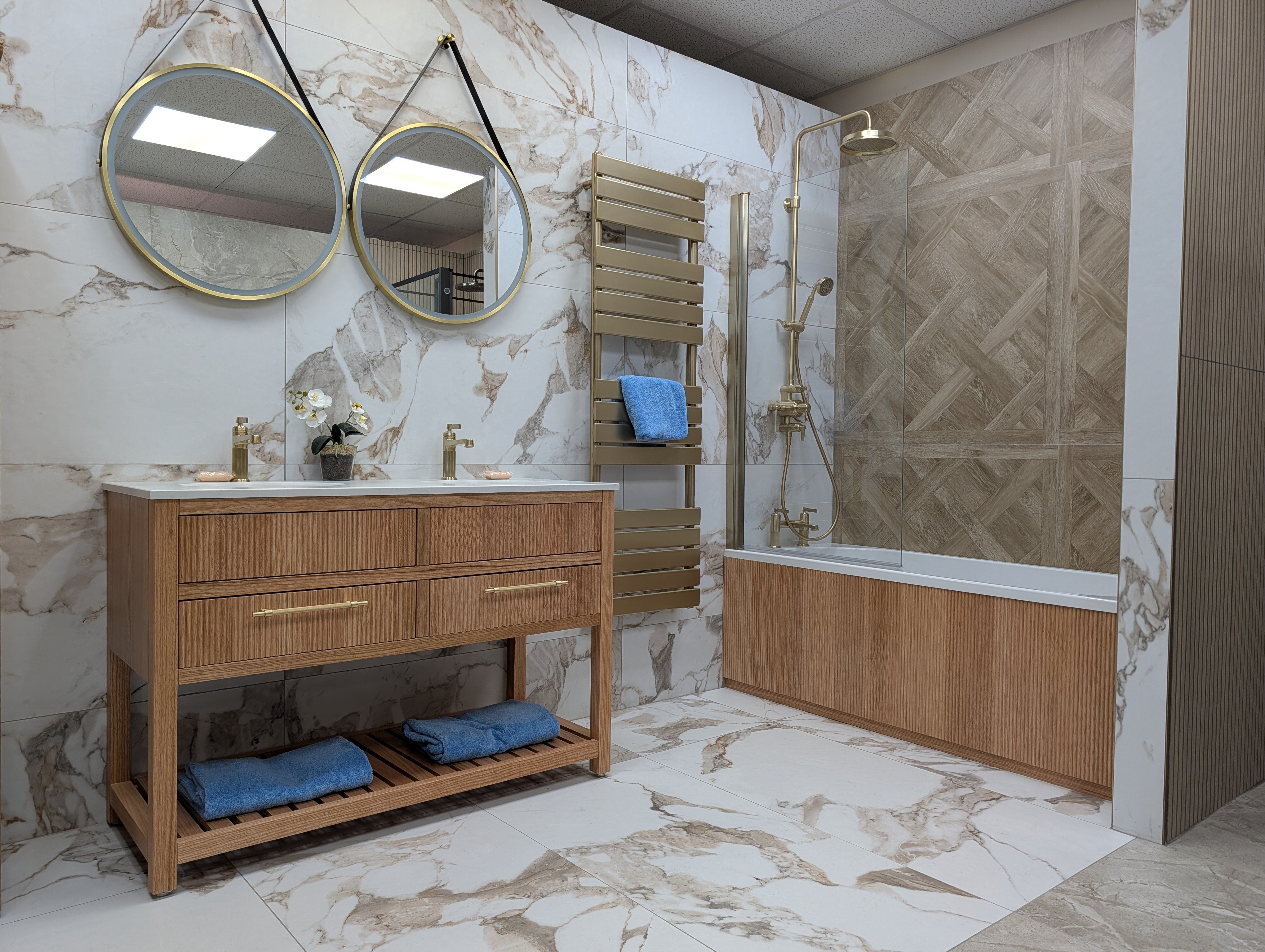Fareham bathroom showroom display featuring natural wood finishes, marble-effect tiles and a double vanity unit.