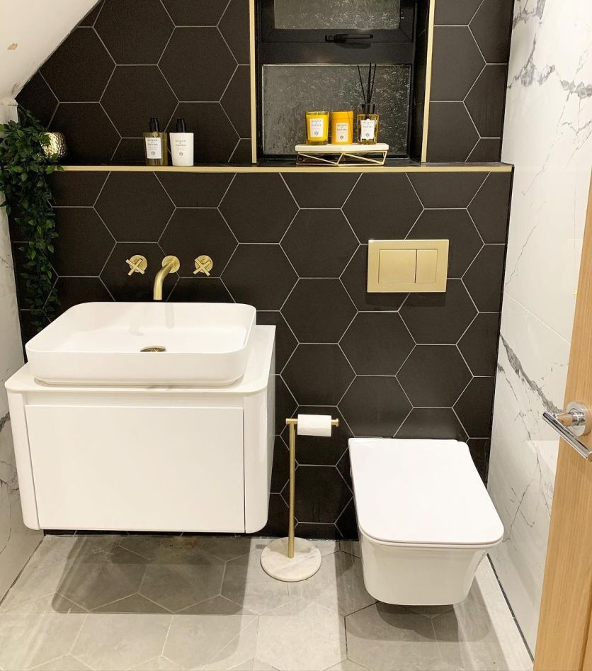 Modern bathroom with black hexagon wall tiles, white wall hung vanity, rectangular countertop basin, wall hung toilet and grey hexagon floor tiles.