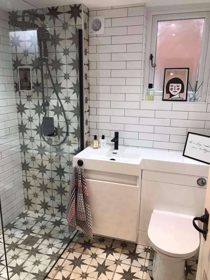 Small contemporary bathroom with star-pattern floor and shower tiles, white subway walls, modern vanity unit and black fixtures.