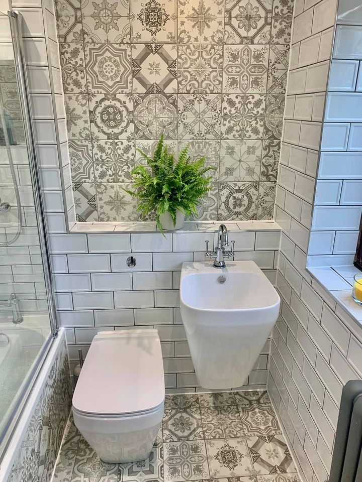 Small bathroom with grey patterned tiles, white metro walls, wall-hung basin and chrome tap, plus a fern for added softness.