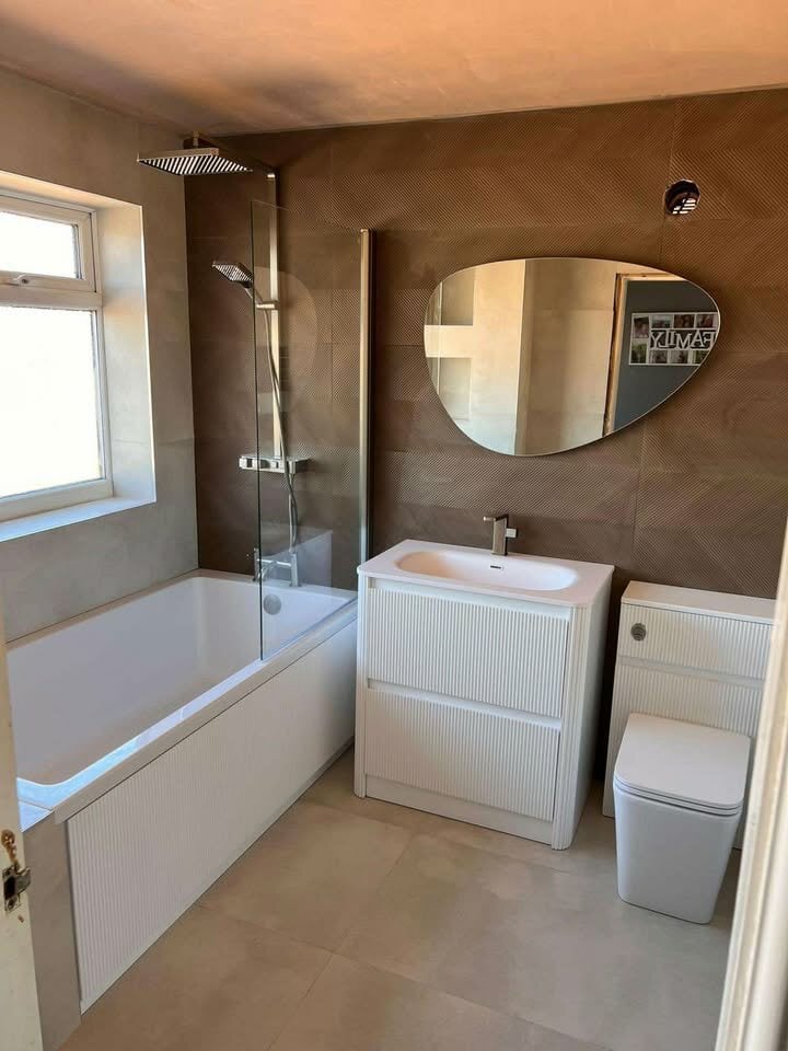 Luxurious white fluted vanity and sleek toilet unit beside a stunning shower bath against textured earth-toned tiles.