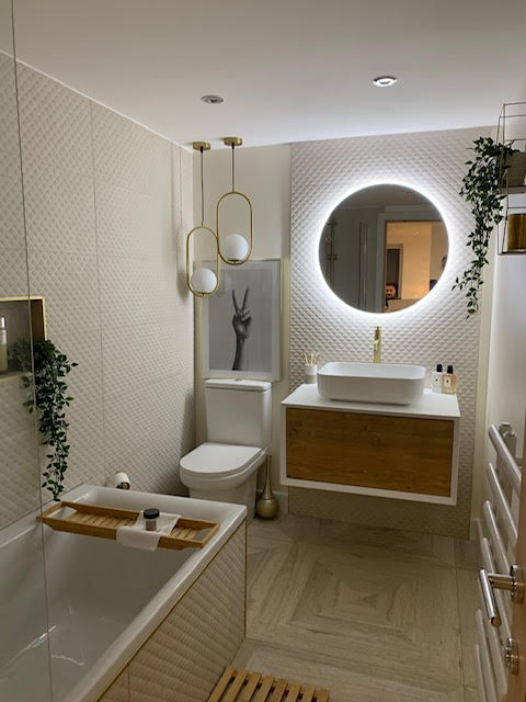 Warm neutral bathroom with Wood Effect beige tiles, gold tap, floating wood vanity and round illuminated mirror.