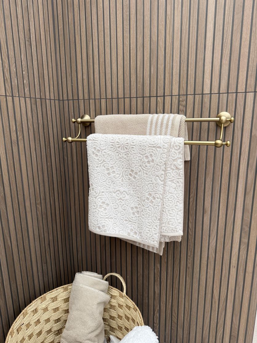 Traditional Warwick brushed gold double towel rail mounted on a textured Ottoman wood slat effect tiled bathroom wall.