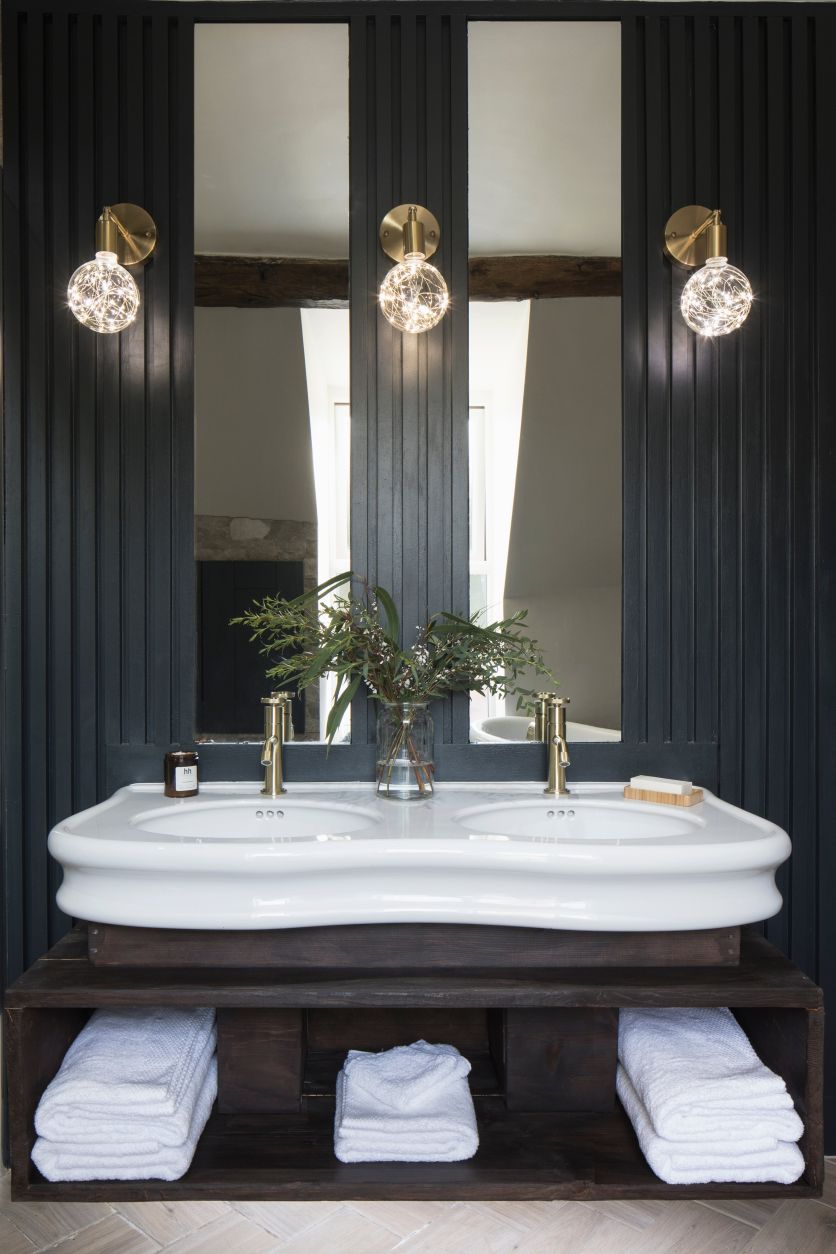 Laine gloss white double console basin and Urban brushed gold taps set against black slatted paneling.