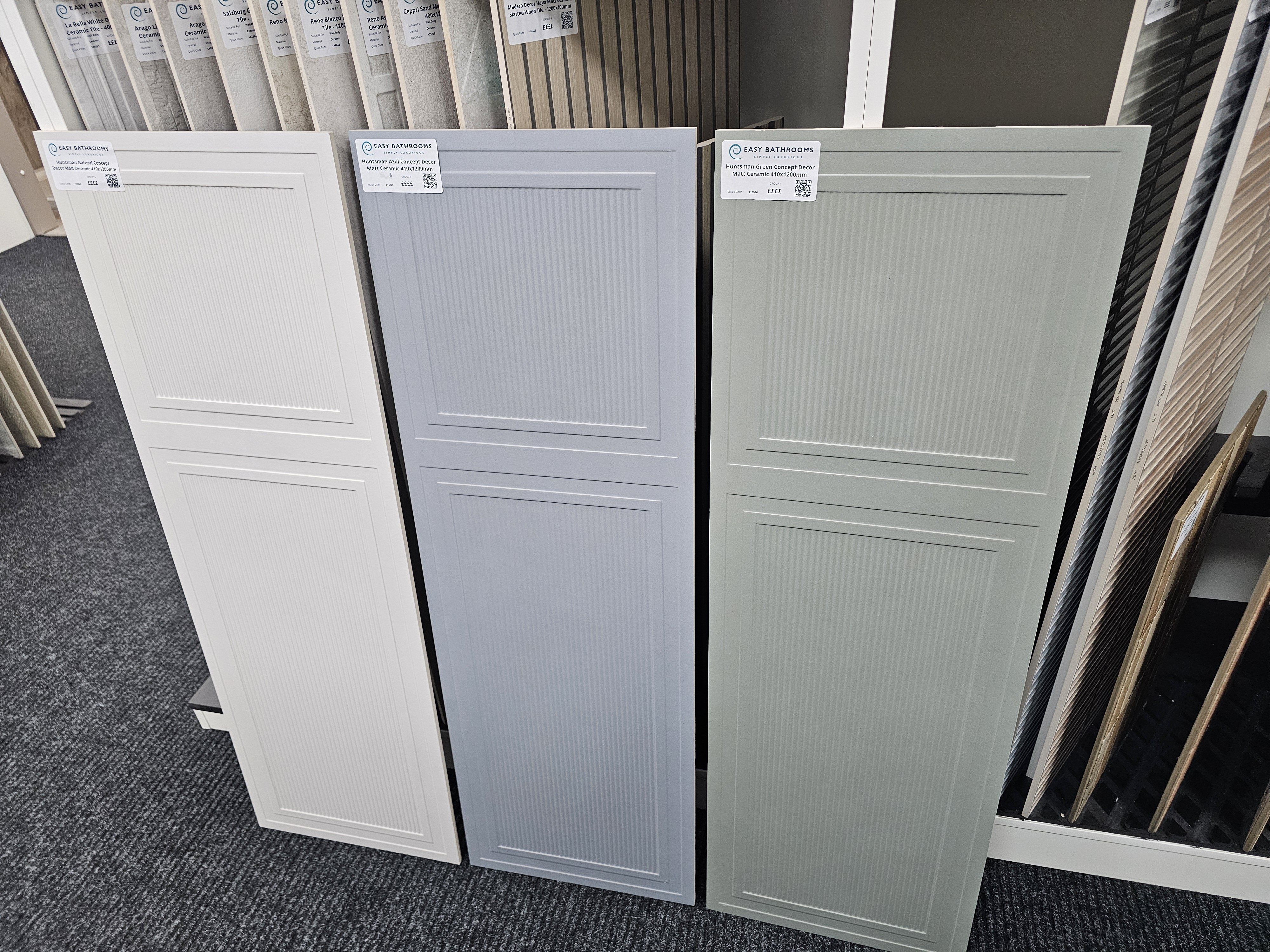 Large-format textured tile samples in white, grey and pale neutral shades.