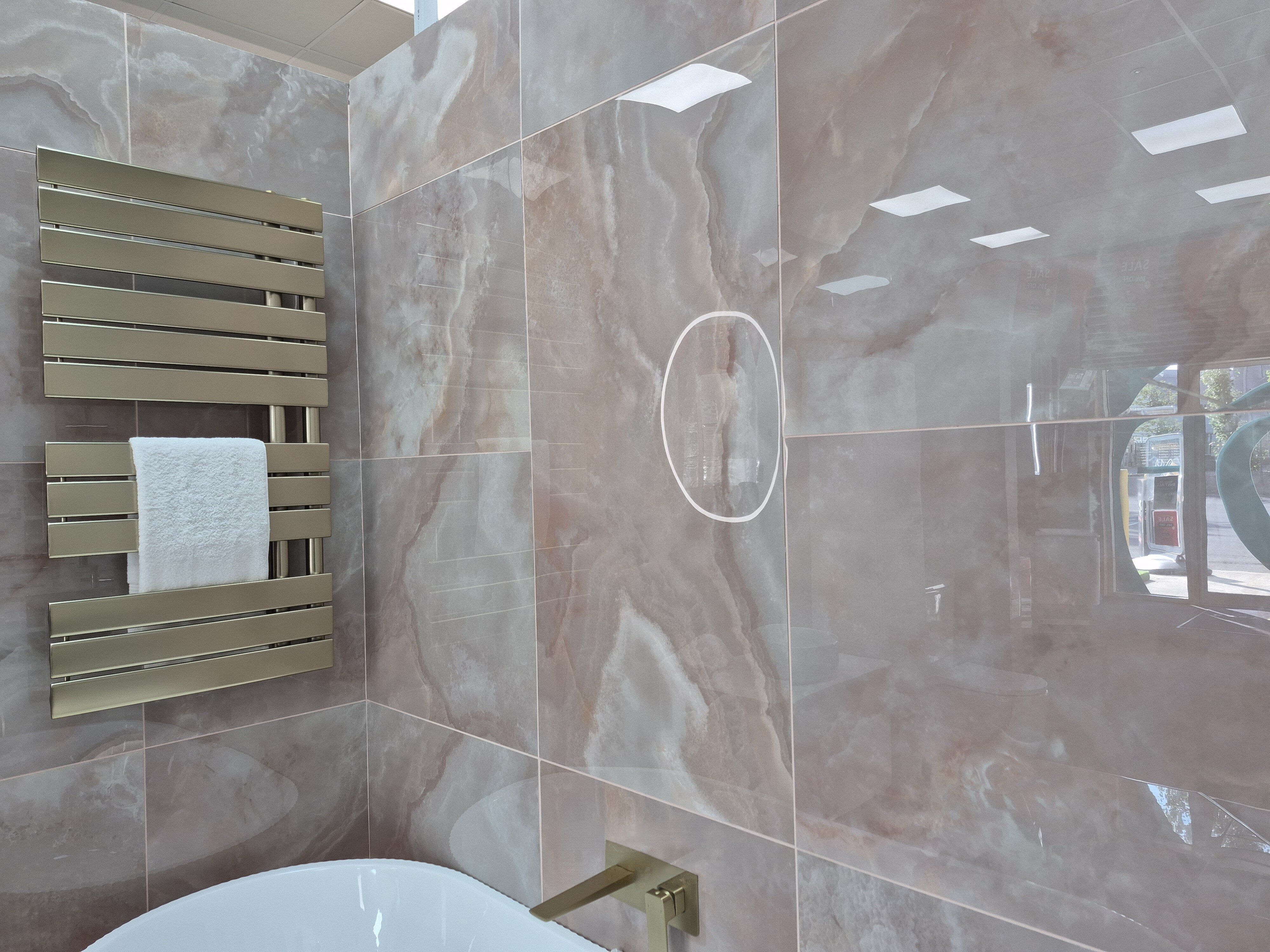 Close-up of the Rosa Coral tiled wall with coordinating heated towel rail and bathroom furniture.