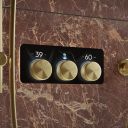 Aqualisa S3 Gold Horizontal Controls detailed view upon a stone brown tiled background