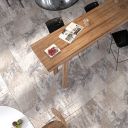 Overhead view of a modern dining room floor paved with Arans Grey 400x600mm stone effect tiles around a wooden dining table