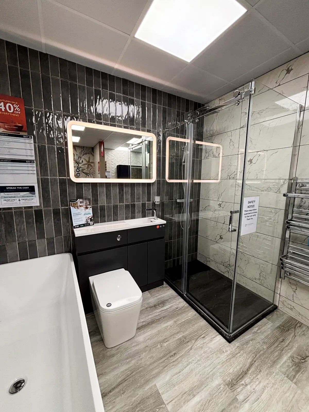 Showroom bathroom display featuring slim vertical tiles, walk in shower and chrome details