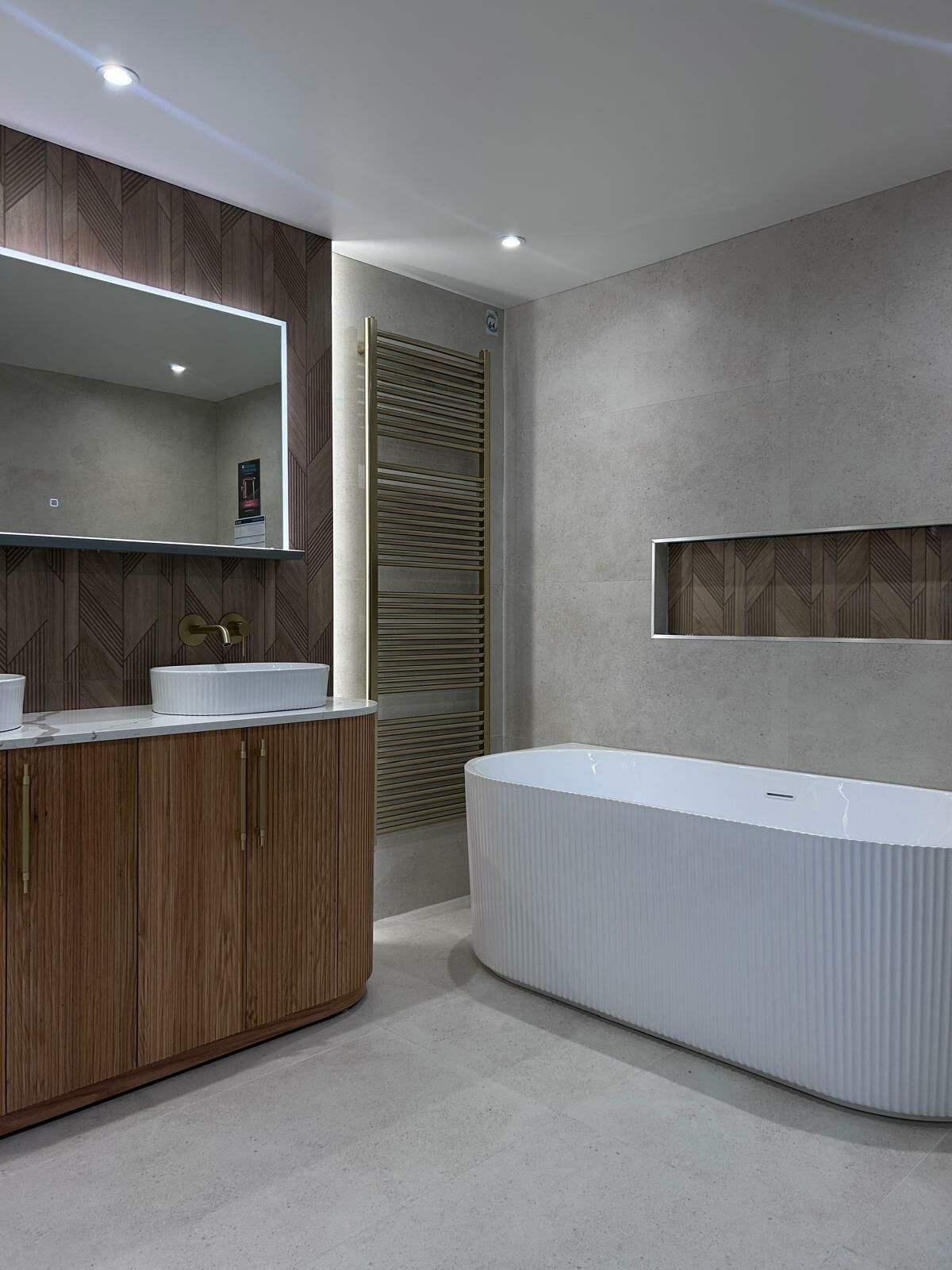 Freestanding bath in the Revel bathroom display at Easy Bathrooms Portsmouth with concrete-effect surfaces and wood-effect features.