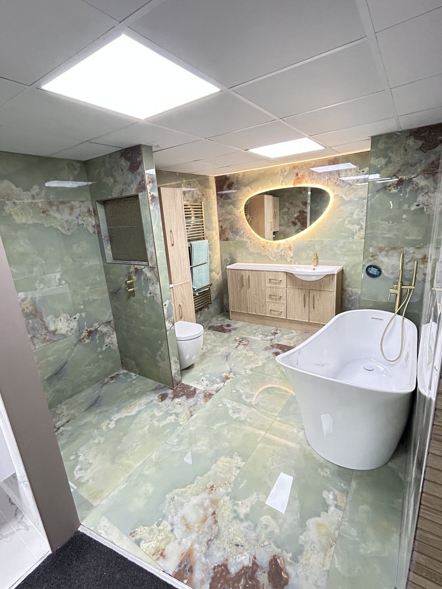 Green onyx tiles and light oak fitted furniture bathroom display