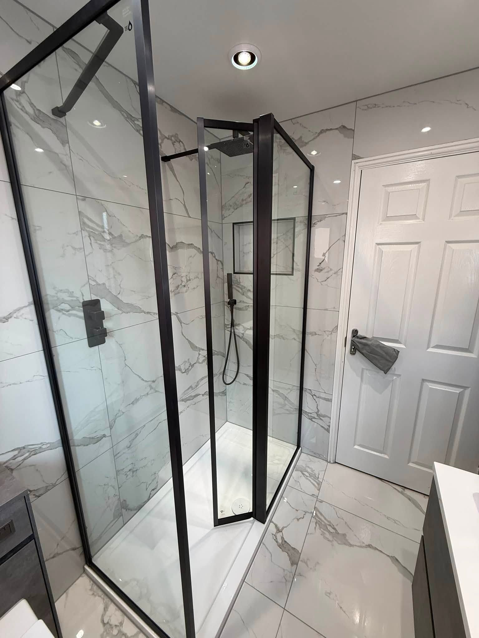Finished Barnsley customer bathroom with a black-framed walk-in shower, marble-effect tiles and modern black fittings.