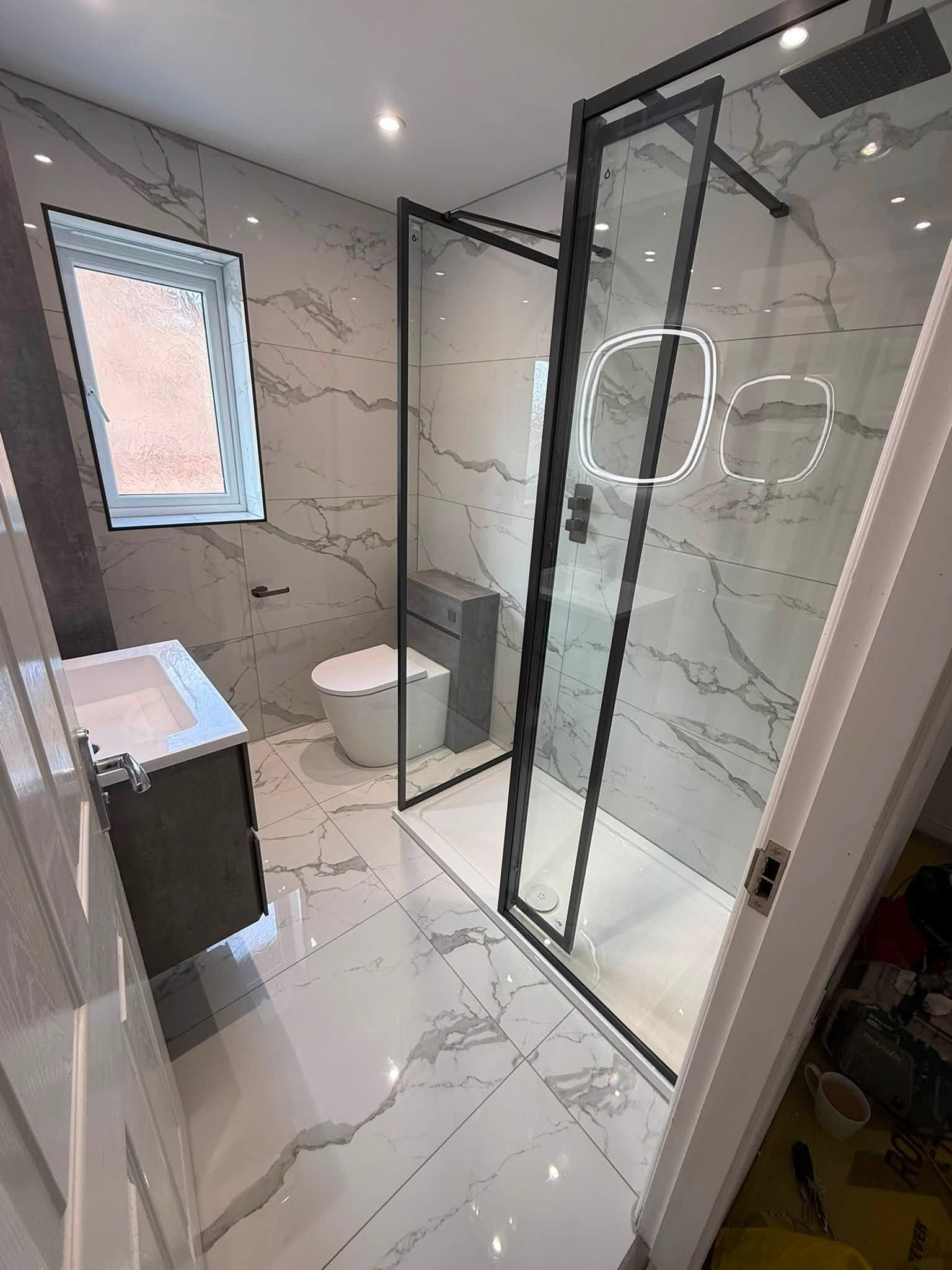 Wide view of the completed bathroom showing the walk-in shower, vanity unit and contemporary tiled finish.