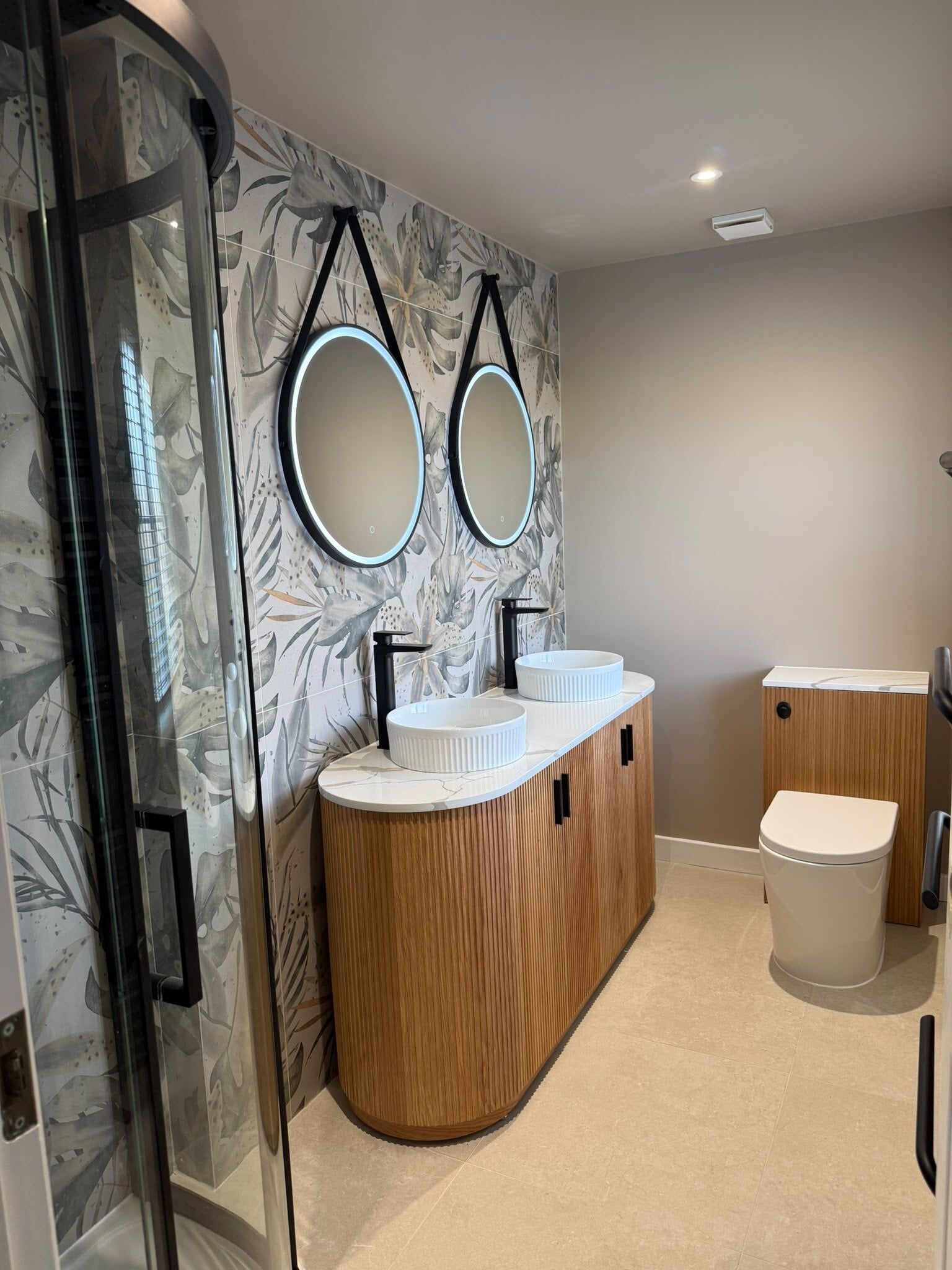 Modern bathroom with LED mirrors, counter top sinks, and botanical tiles