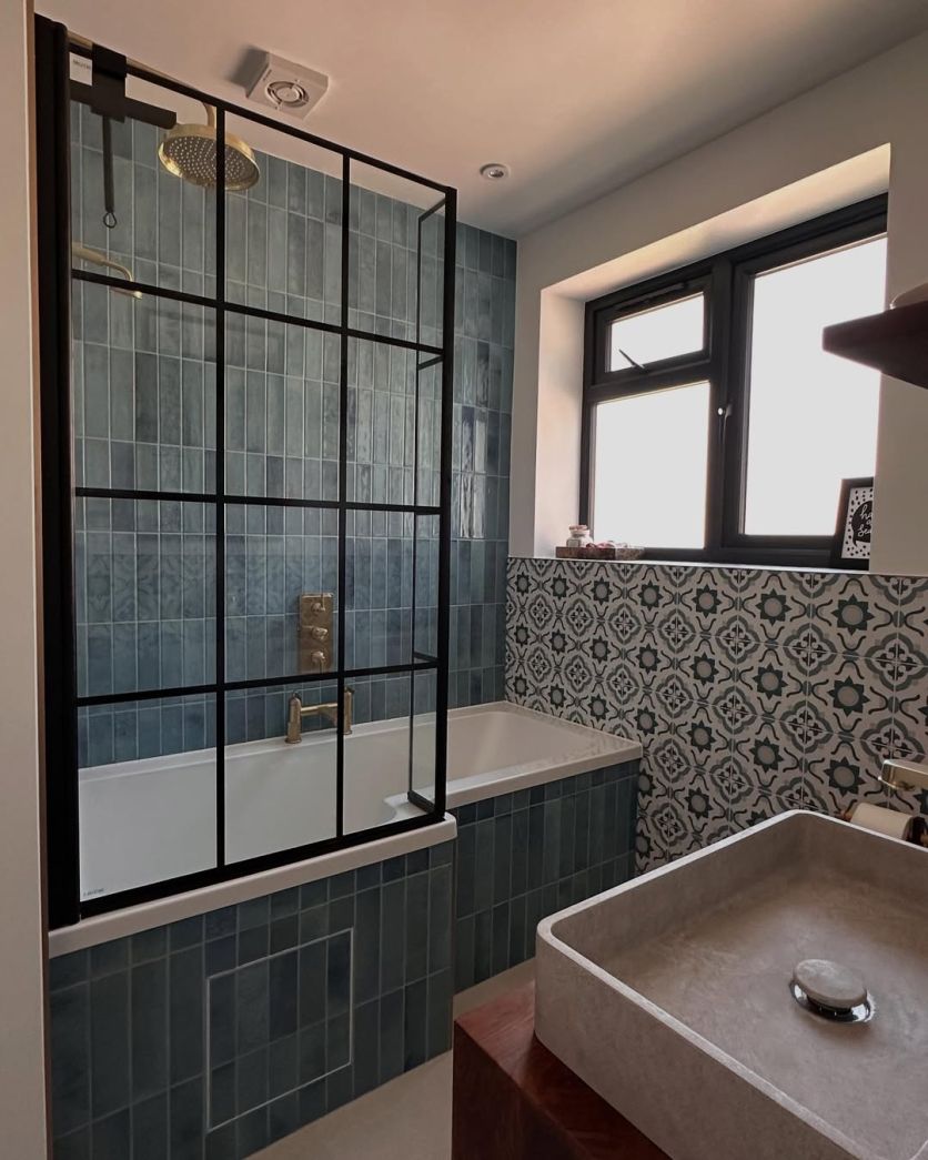 small modern blue bathroom with brick tiled shower and patterned tile wall