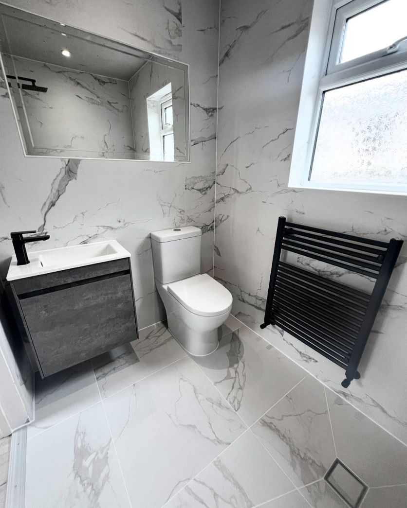 Marbella Marron marble tiles with an Odion concrete vanity and Neptune matt black towel rail in a modern cloakroom.