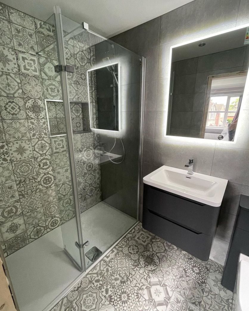Modern grey bathroom with patterned tiles, a walk-in shower, charcoal vanity unit and an illuminated LED mirror.