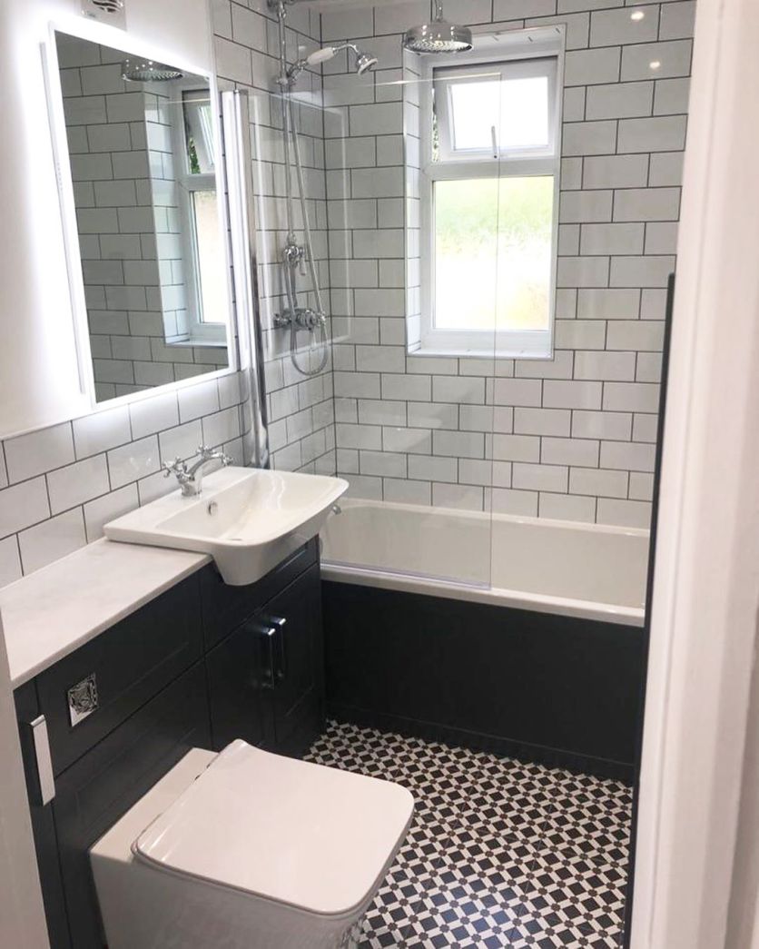 A sophisticated monochrome bathroom featuring a white bath with a black side panel, complemented by a chrome rainfall shower and traditional handset.