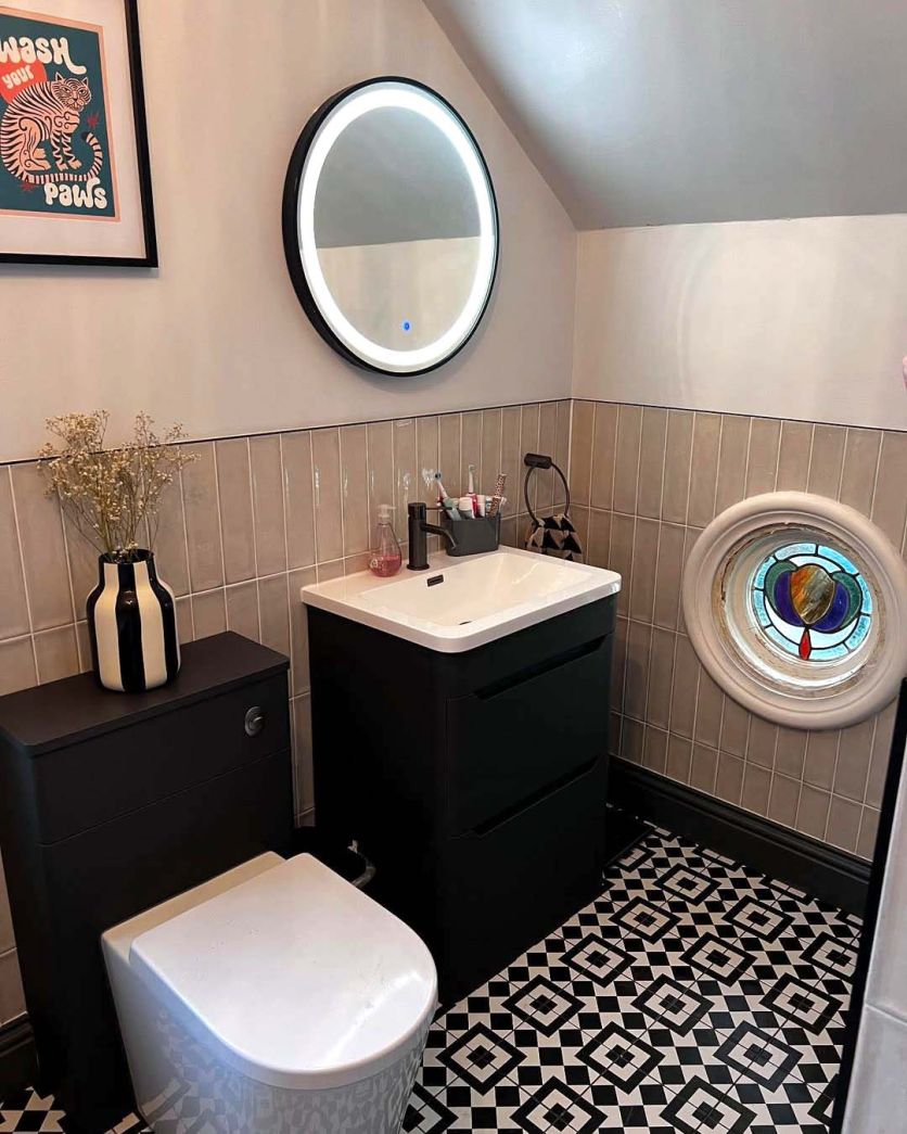 A stylish monochrome cloakroom featuring Cascais Mix 6 patterned floor tiles and Babylon Brown gloss brick wall tiles, complemented by an Ellis matt black floor-standing vanity and a large Avery round LED heated mirror.