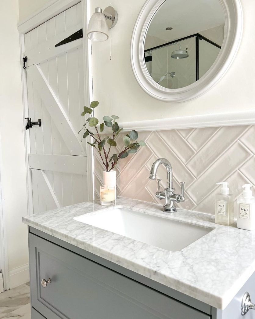 Classic cottage-style bathroom with grey vanity, marble countertop, herringbone gloss tiles and traditional chrome tap.