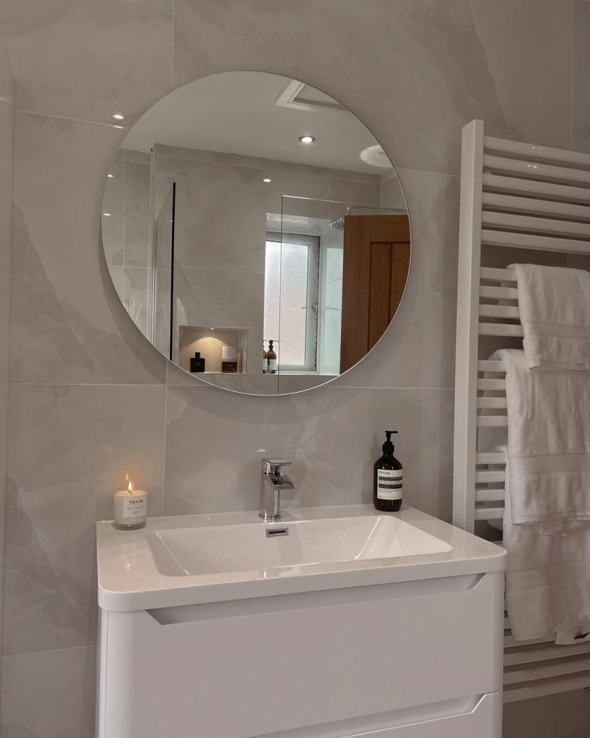 Osaka white polished tiles background an Ellis matt white vanity, Felix round mirror, and Teon white towel rail.