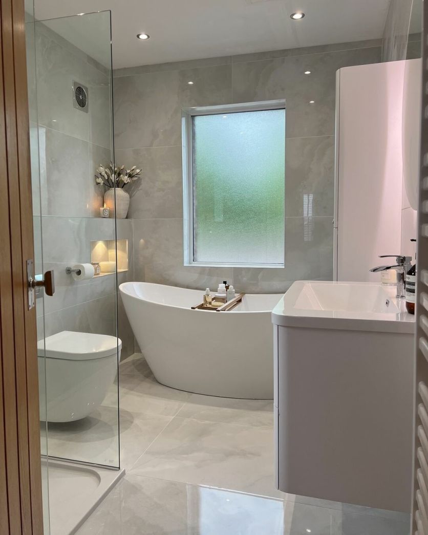 Osaka white polished onyx tiles frame a Lambi freestanding bath, Oscar toilet, and Ellis white vanity unit.