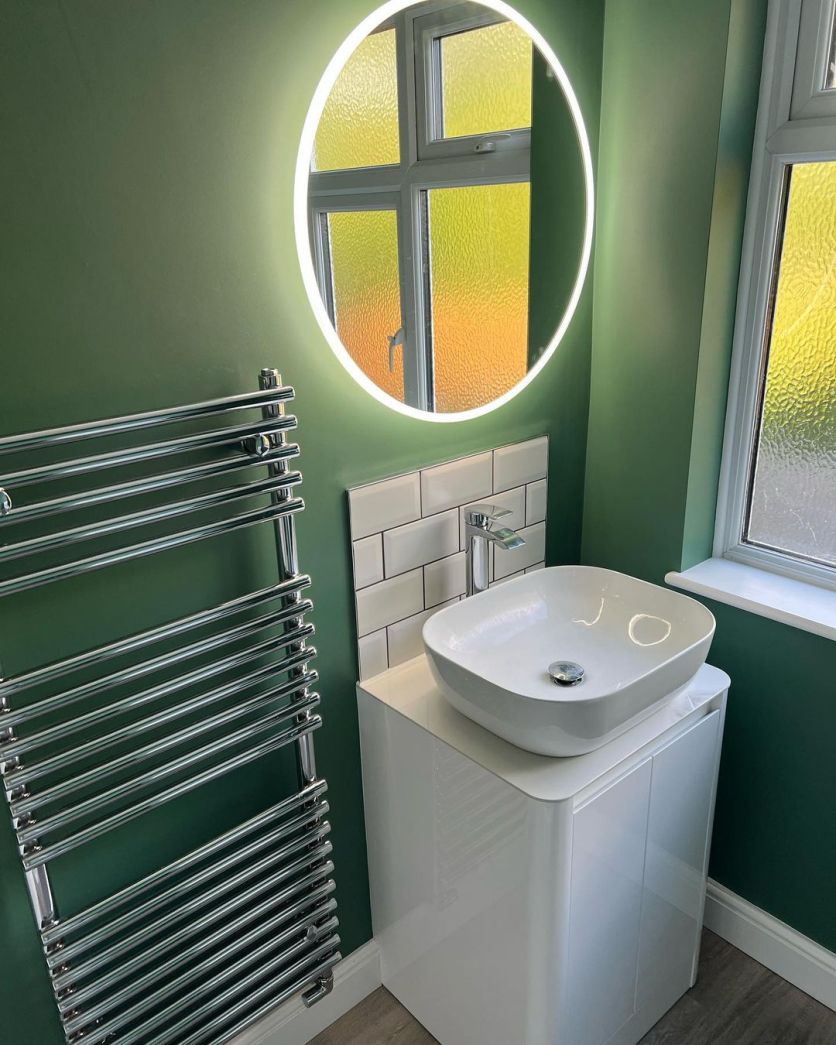 A modern cloakroom featuring a white gloss vanity unit with a square countertop basin and chrome tap, set against sage green walls.