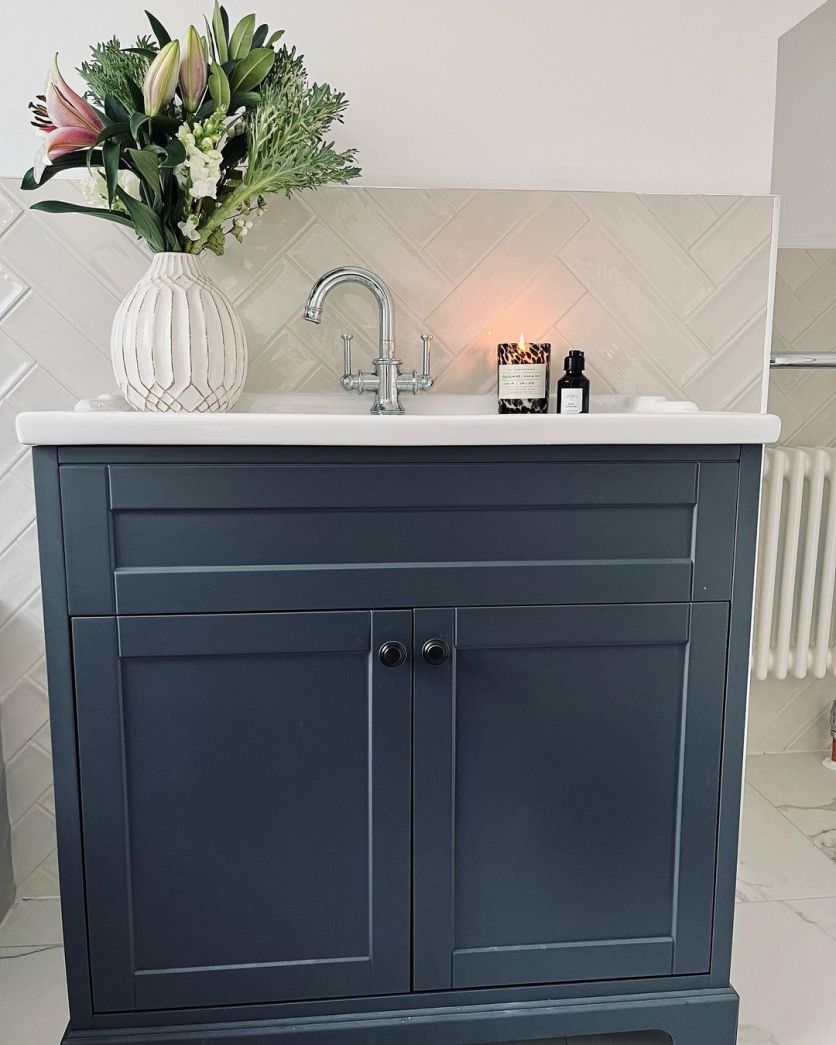 Traditional bathroom vanity in midnight grey with chrome taps, herringbone gloss brick tiles and styled flowers on the basin.