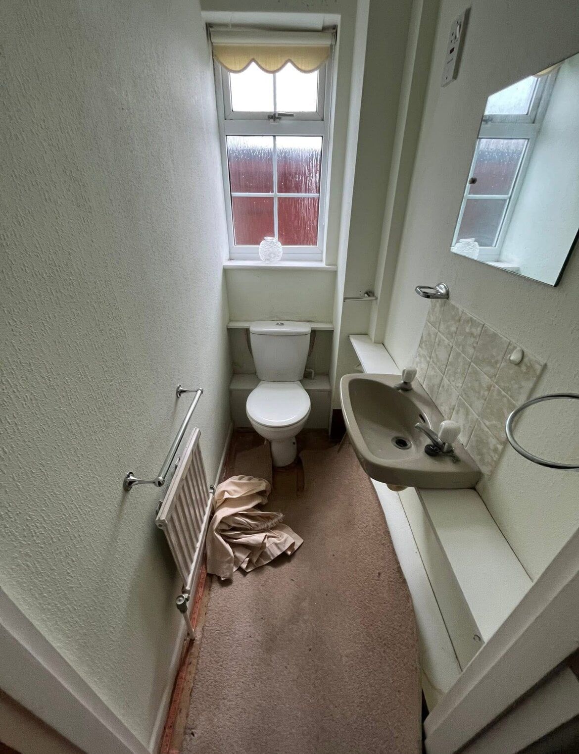 Cloakroom before renovation with an older toilet, basin and unfinished flooring.