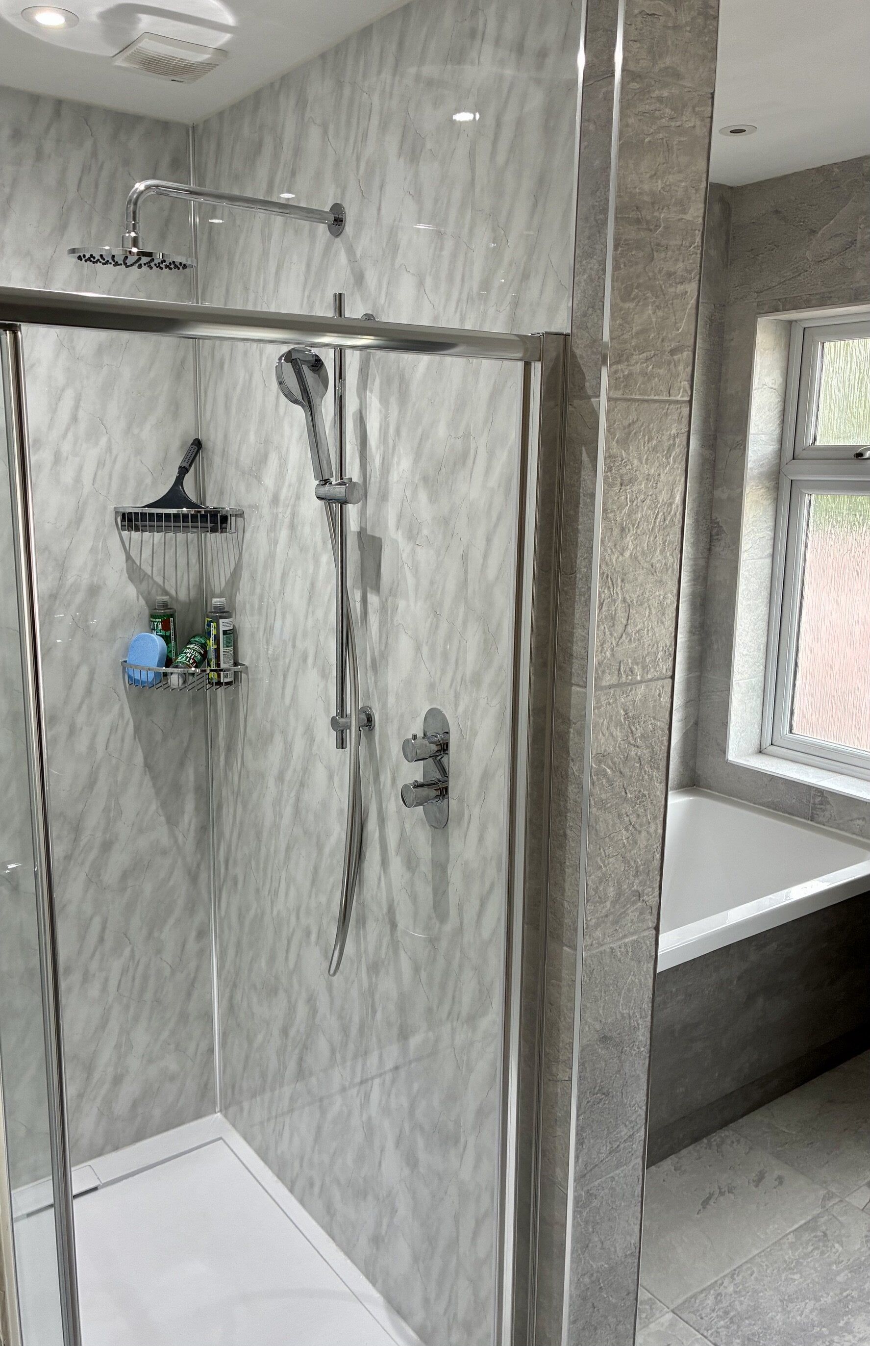 Completed walk-in shower with chrome fittings and grey stone-effect wall tiles.