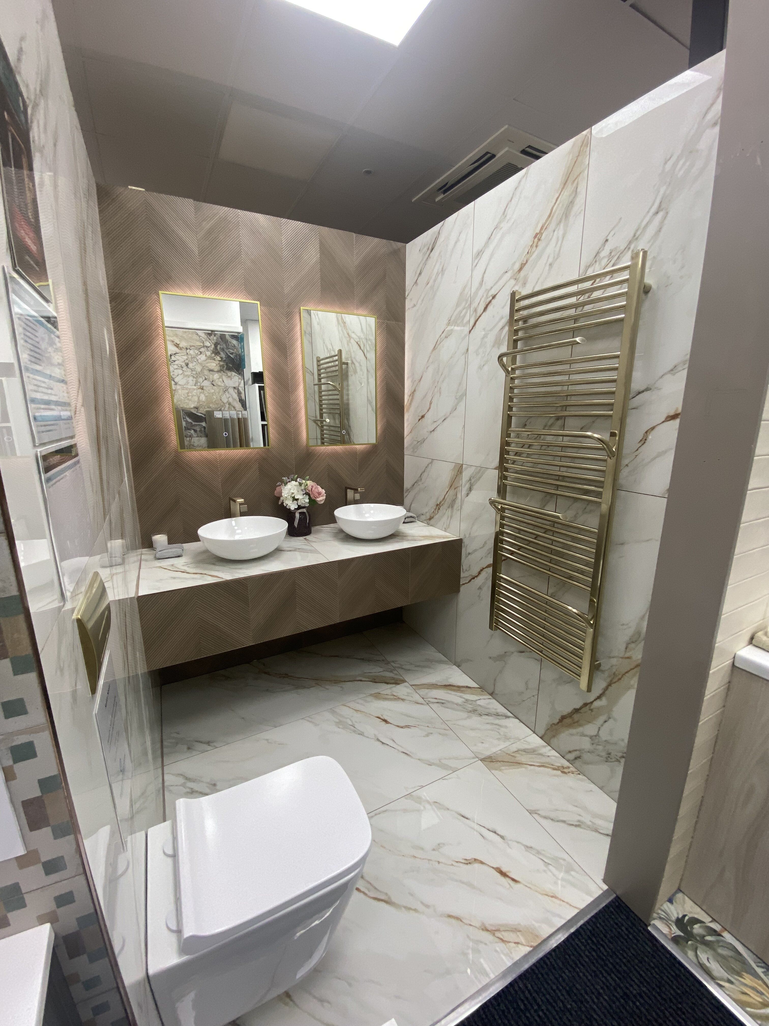 New bathroom display at Easy Bathrooms Newbury featuring neutral tiles, white sanitaryware and warm wood-effect finishes.