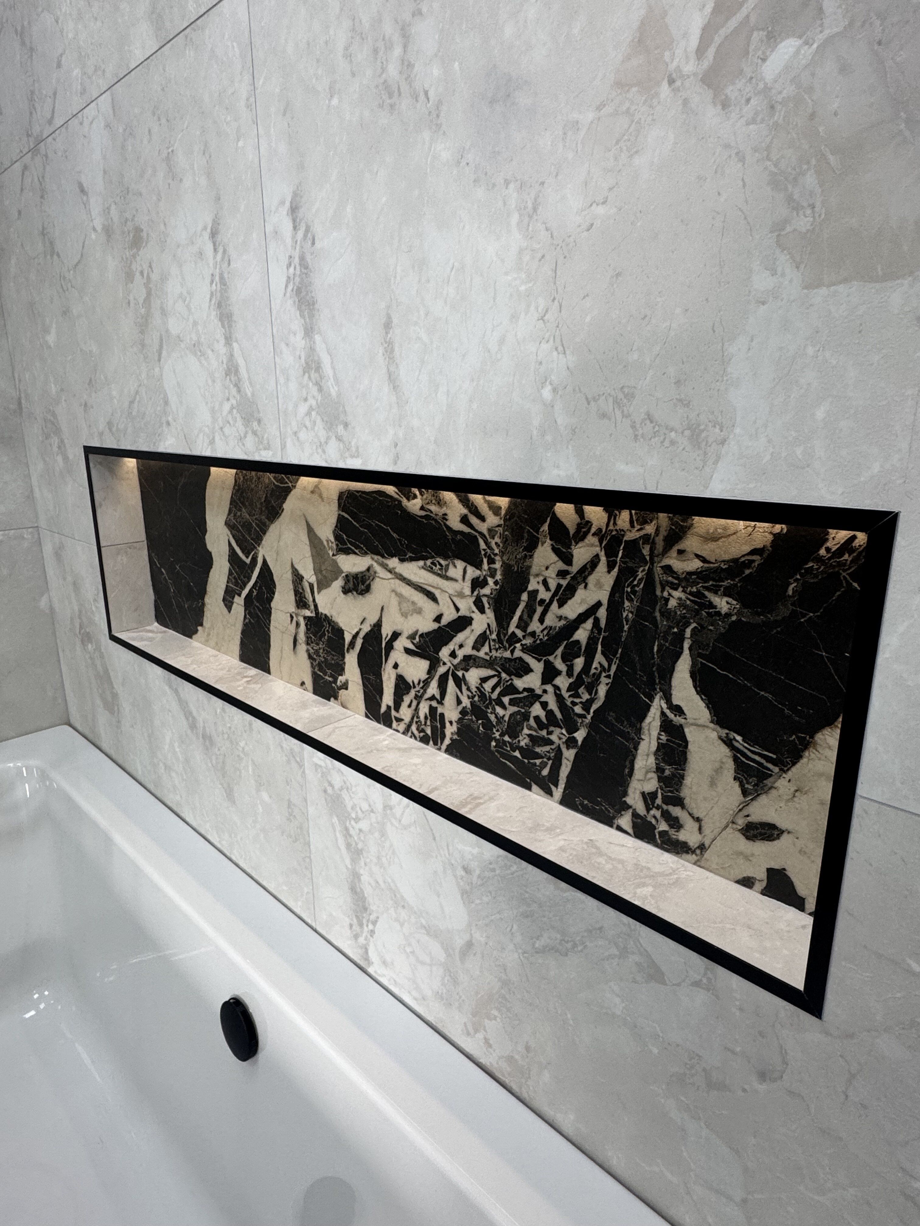 Built-in bath with marble-effect wall and floor tiles in the Leeds Seacroft bathroom display.
