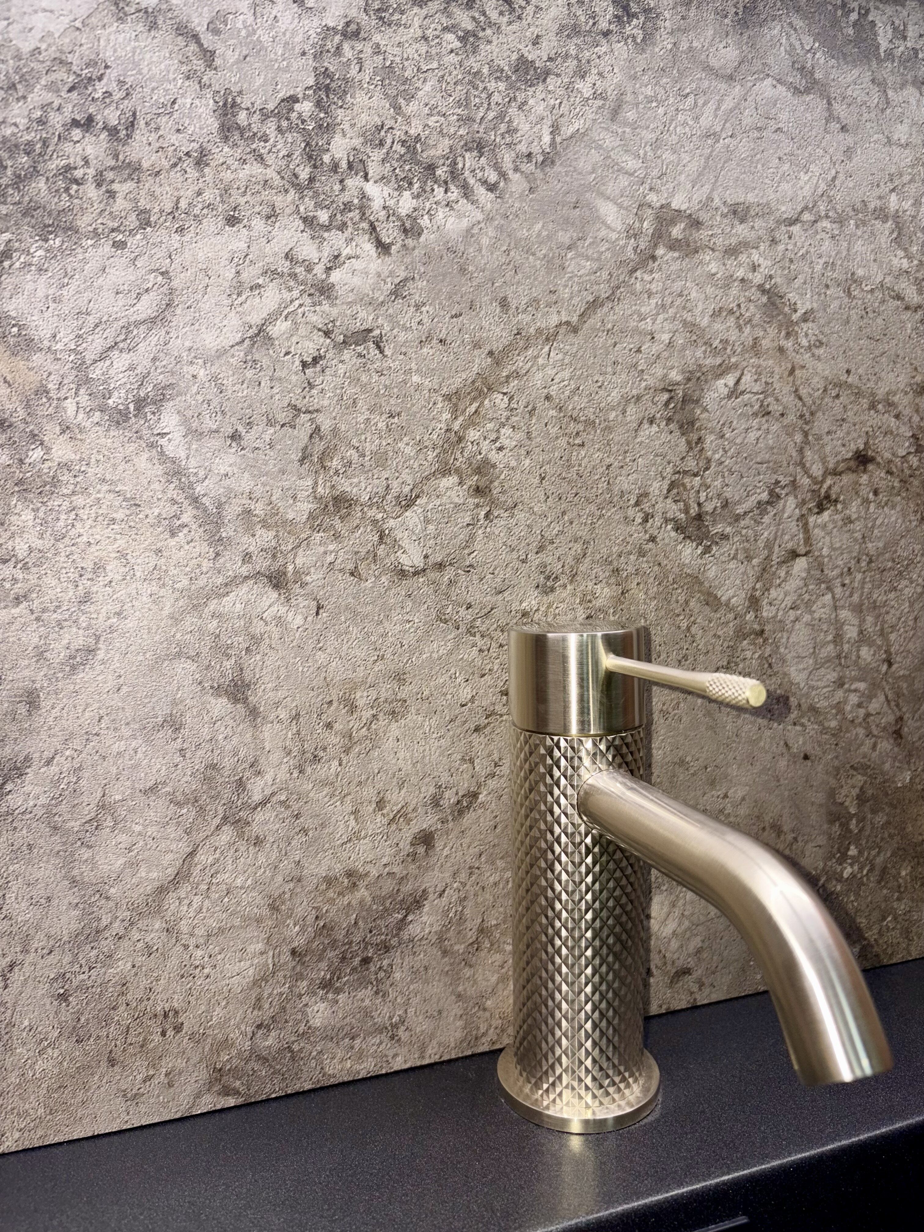 Light stone-effect Pristina PVC wall panel displayed with a brushed metal basin tap at Easy Bathrooms Nottingham Castle.