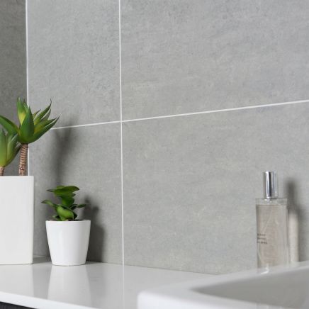 Modern bathroom vanity wall clad in Monarch Mid Grey Gloss 300x600mm tiles behind potted plants.