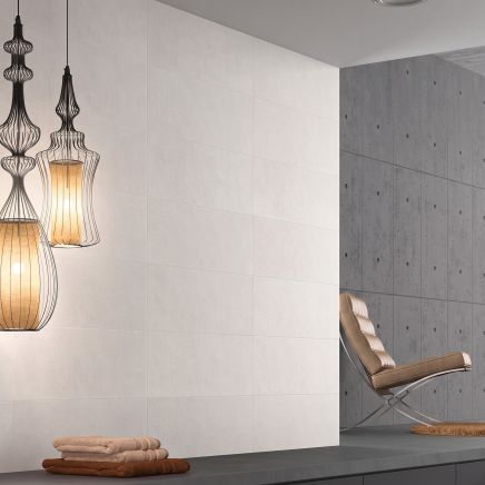 Modern living room feature wall clad in Moonlight Ceniza Ceramic Wall Tiles 250x750mm with decorative wire pendant lights.