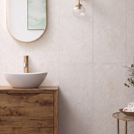 Modern bathroom wall vertically tiled in Kenya Marfil Ceramic Wall Tiles behind a wooden vanity with brass mixer.