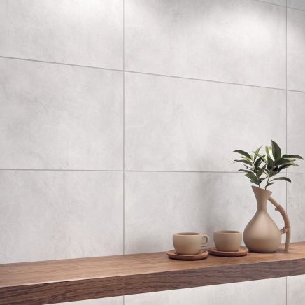 Wall tiled in Gandi Concrete Perla Matt Porcelain Tiles 300x600mm behind a wooden shelf with tea cups.