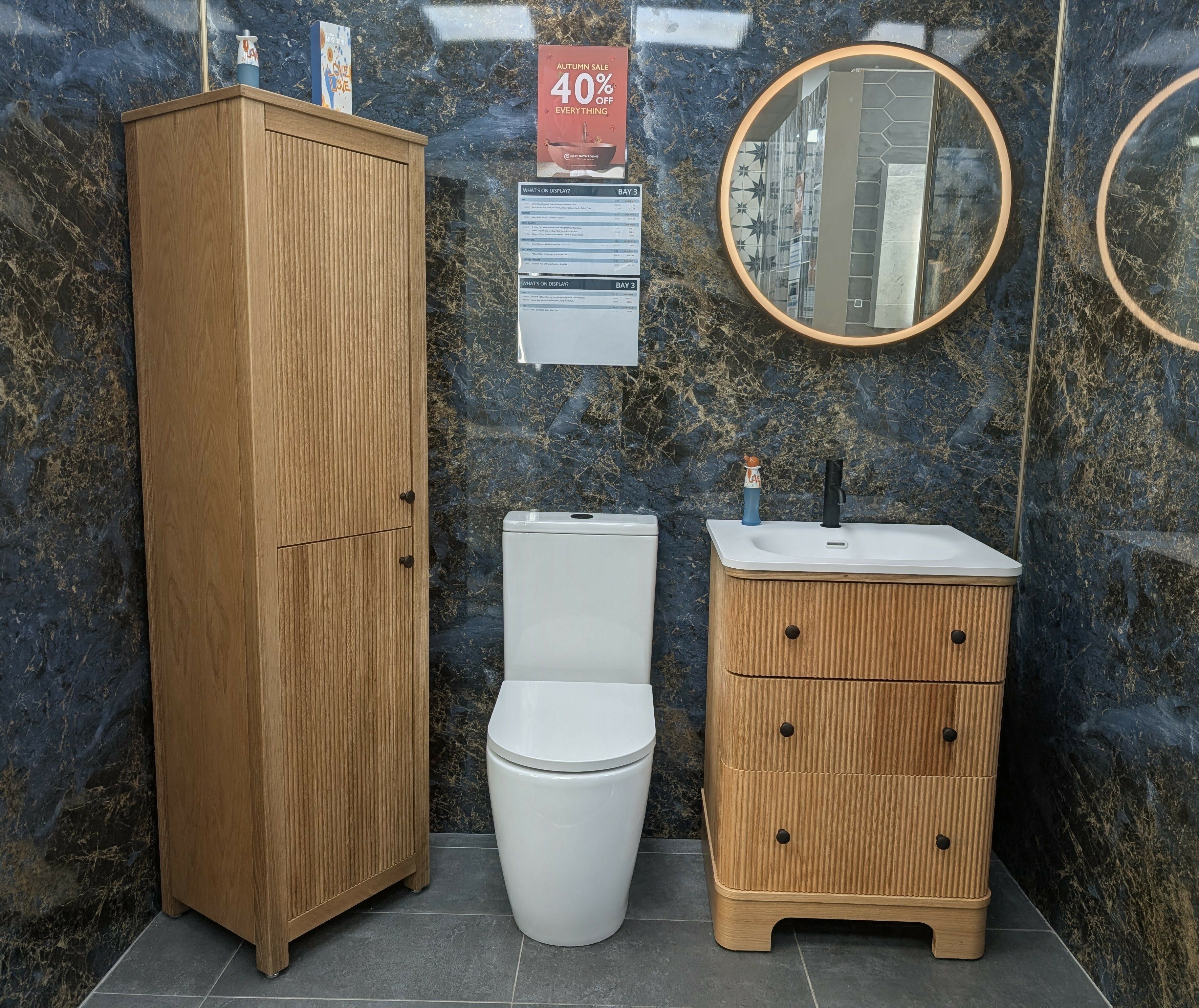 New bathroom display at Easy Bathrooms Stoke-on-Trent featuring a Hayward natural oak vanity unit, dark blue Pristina wall panels and matching bathroom storage.