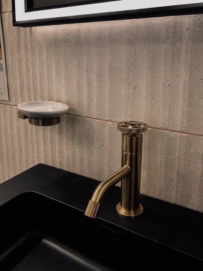 Brushed gold soap dish and basin mono tap with ribbed organic natural stone effect tiles