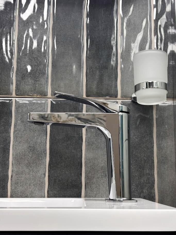 Showroom display featuring chrome tap and slim vertical ceramic tiles.