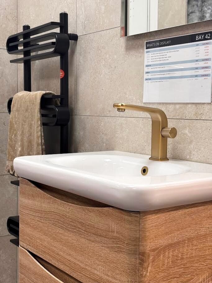 Bathroom showroom display featuring wood vanity unit with porcelain sink and gold tap