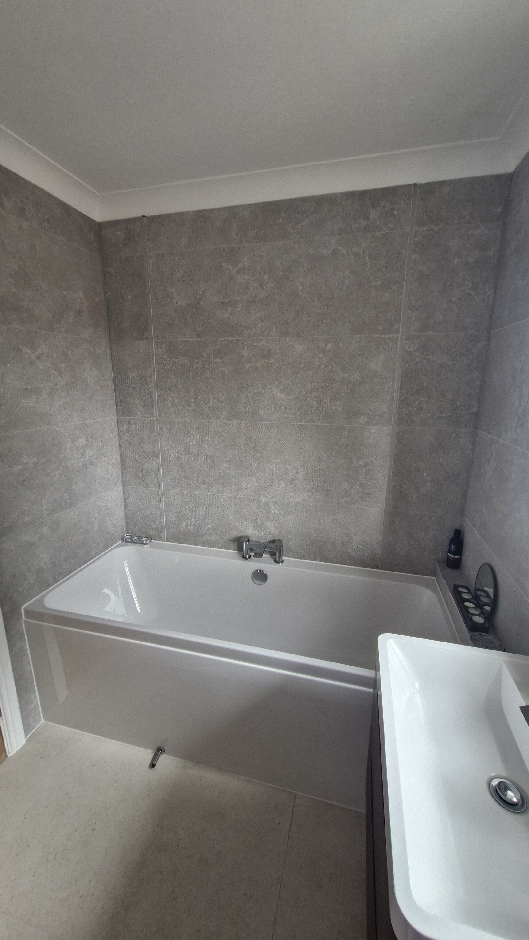 Norwich customer bathroom with bath, neutral wall tiles and integrated ambient LED lighting.