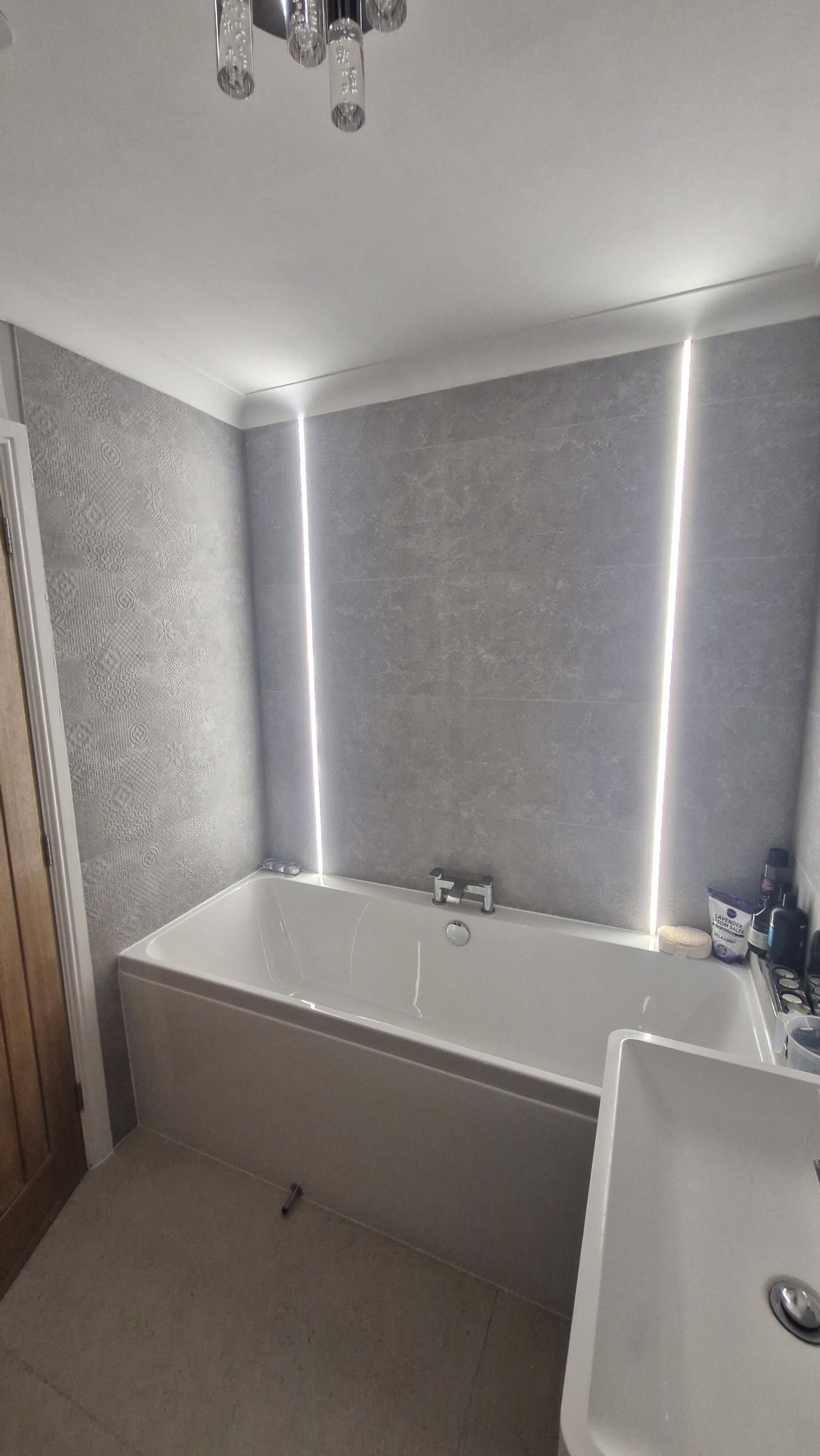 Completed bathroom from Easy Bathrooms Norwich featuring tiled-in LED strip lighting around the bath and soft neutral finishes.