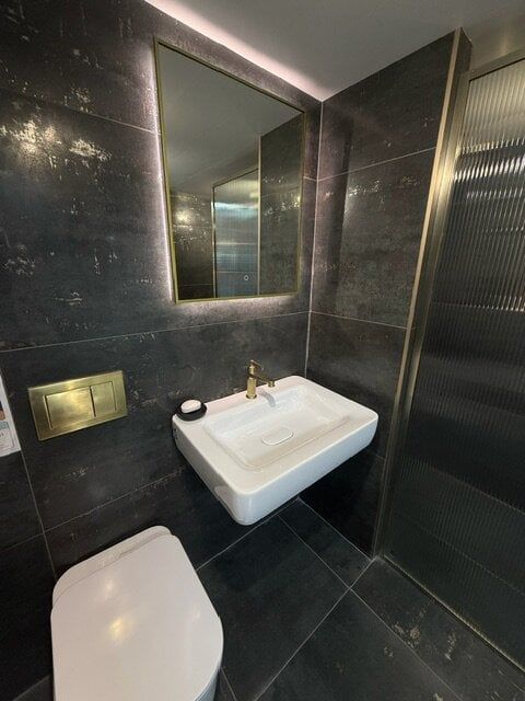 White basin and illuminated mirror set against dark charcoal bathroom tiles at Easy Bathrooms High Wycombe.