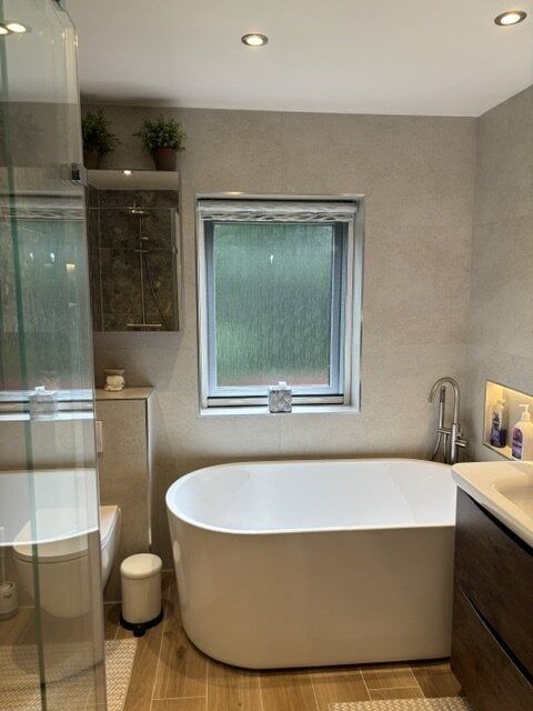 Wide view of the completed bathroom featuring a freestanding bath, glass shower screen and neutral finishes.