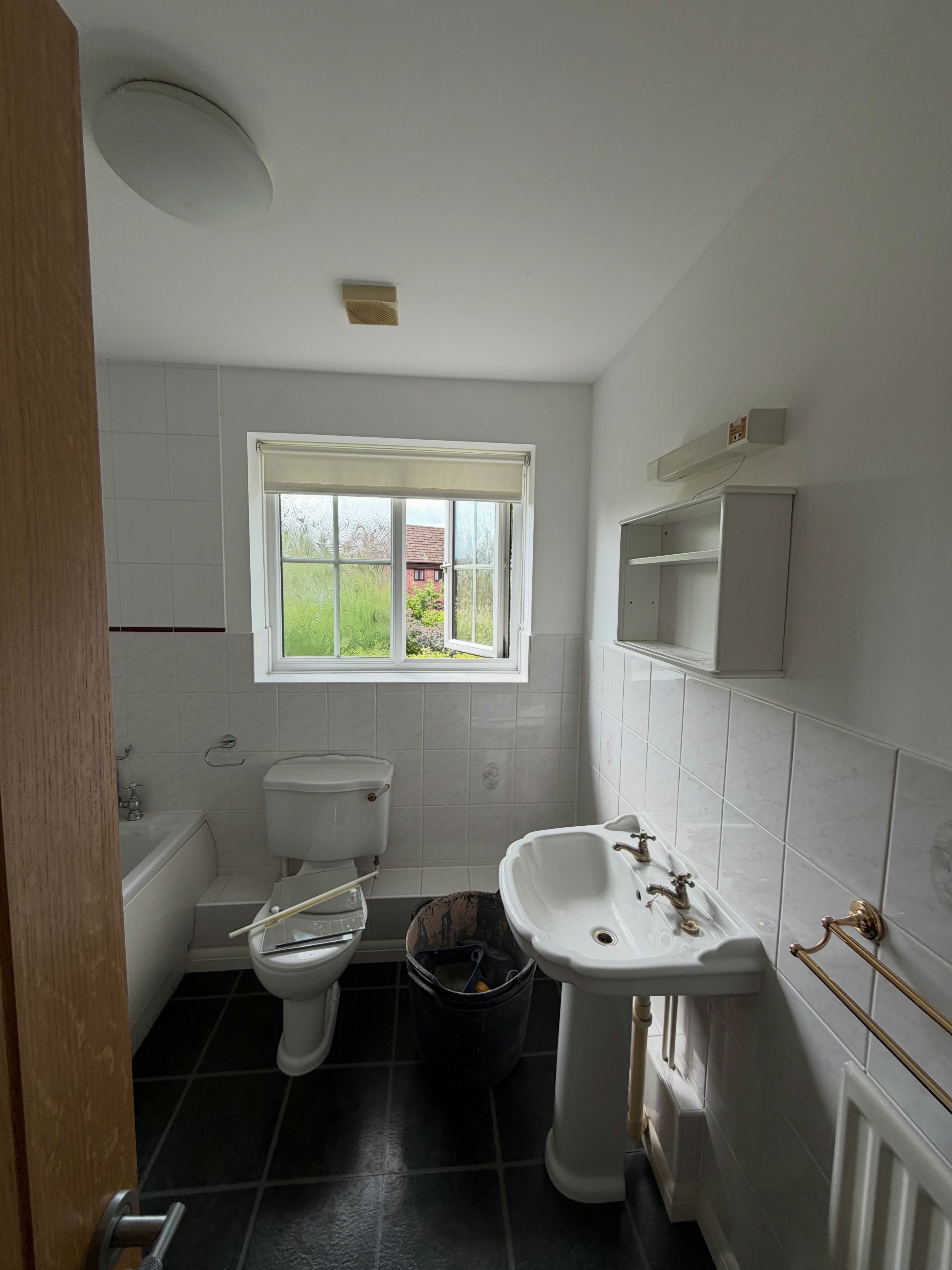Bathroom before renovation showing the original layout with basin, toilet and dark flooring.
