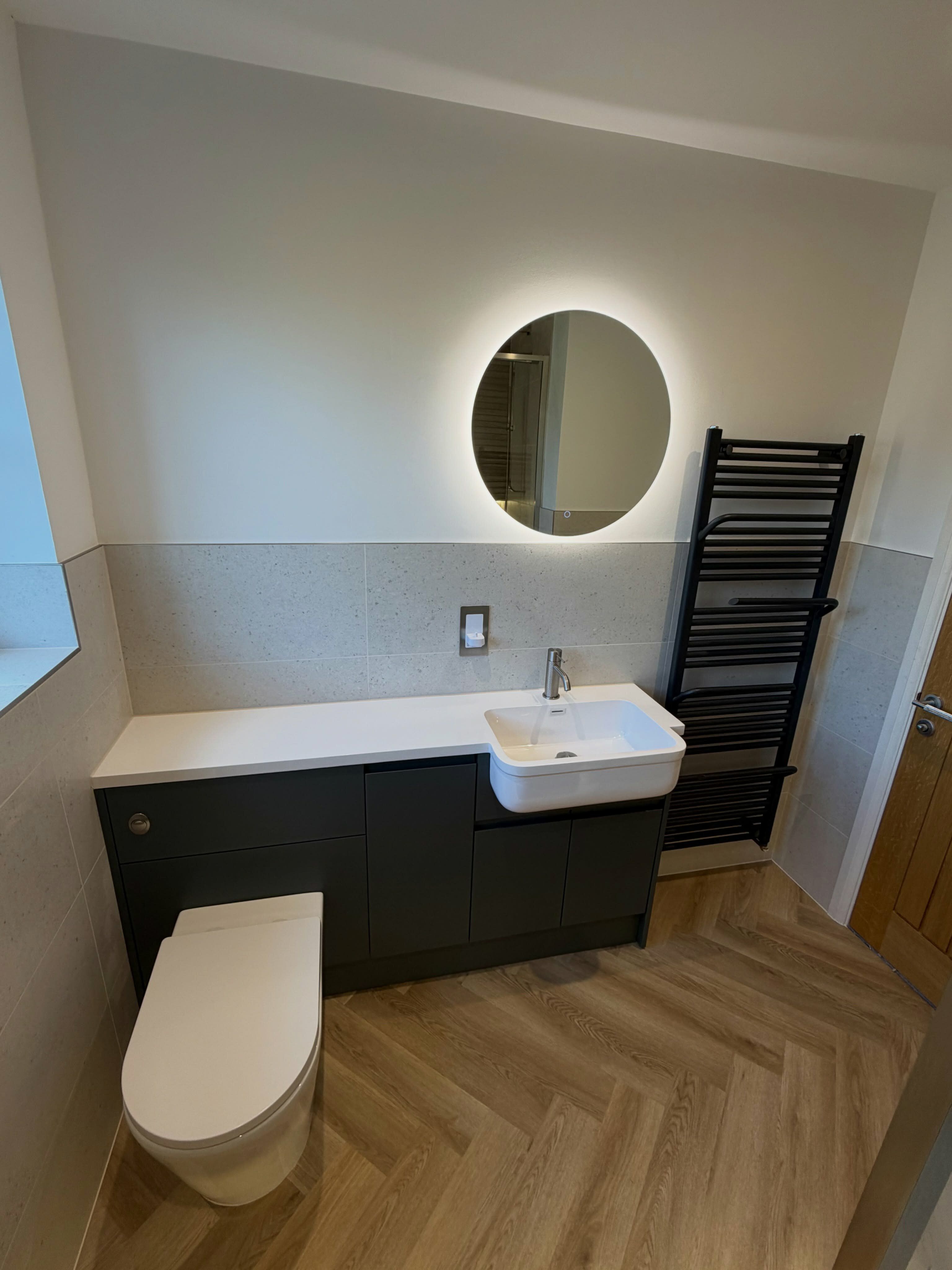 Gingham fitted bathroom furniture with illuminated mirror and built-in storage in a Norwich customer renovation.